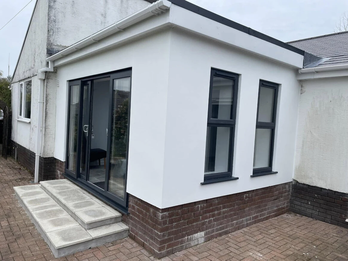 Finished white rear extension with black-framed doors and windows in Swansea
