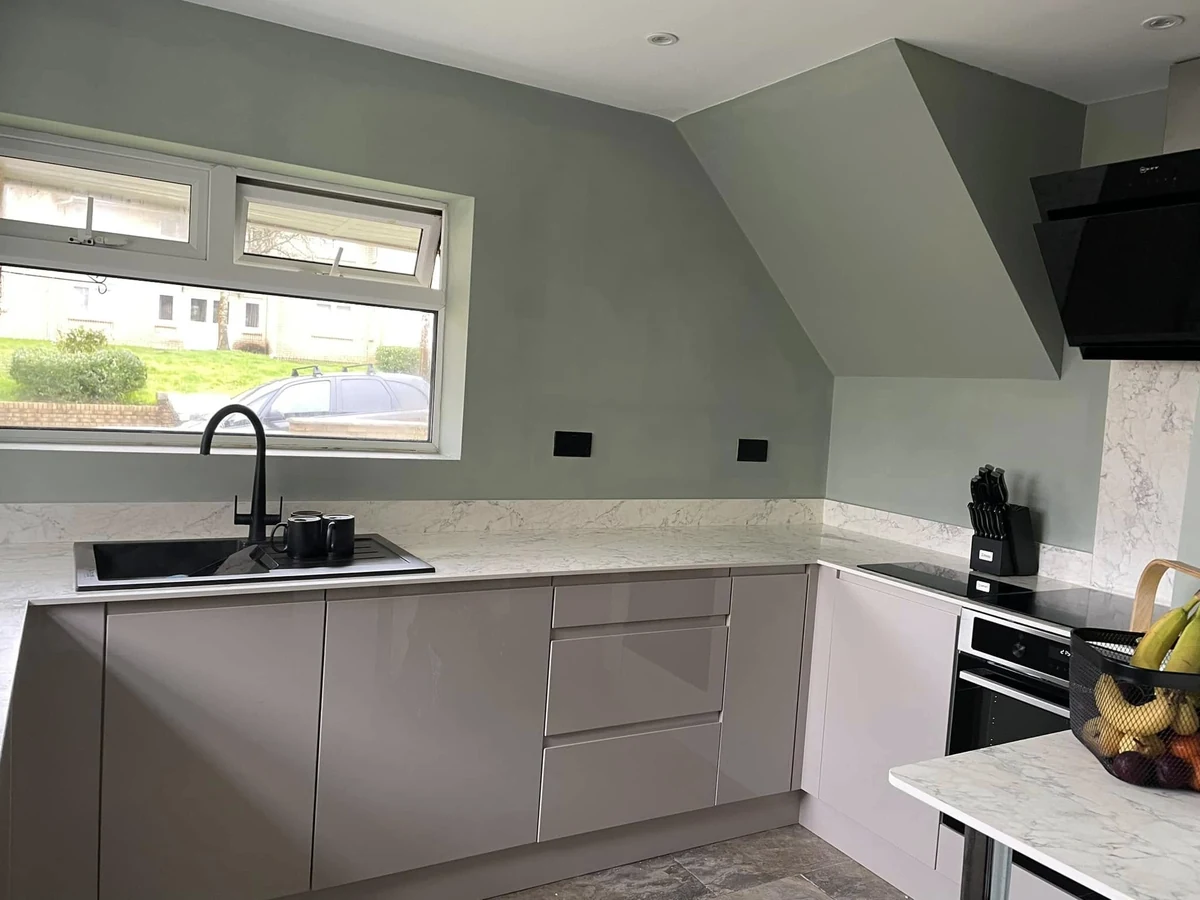 Grey fitted kitchen with a light worktop and black tap, photographed near the end of a Swansea project