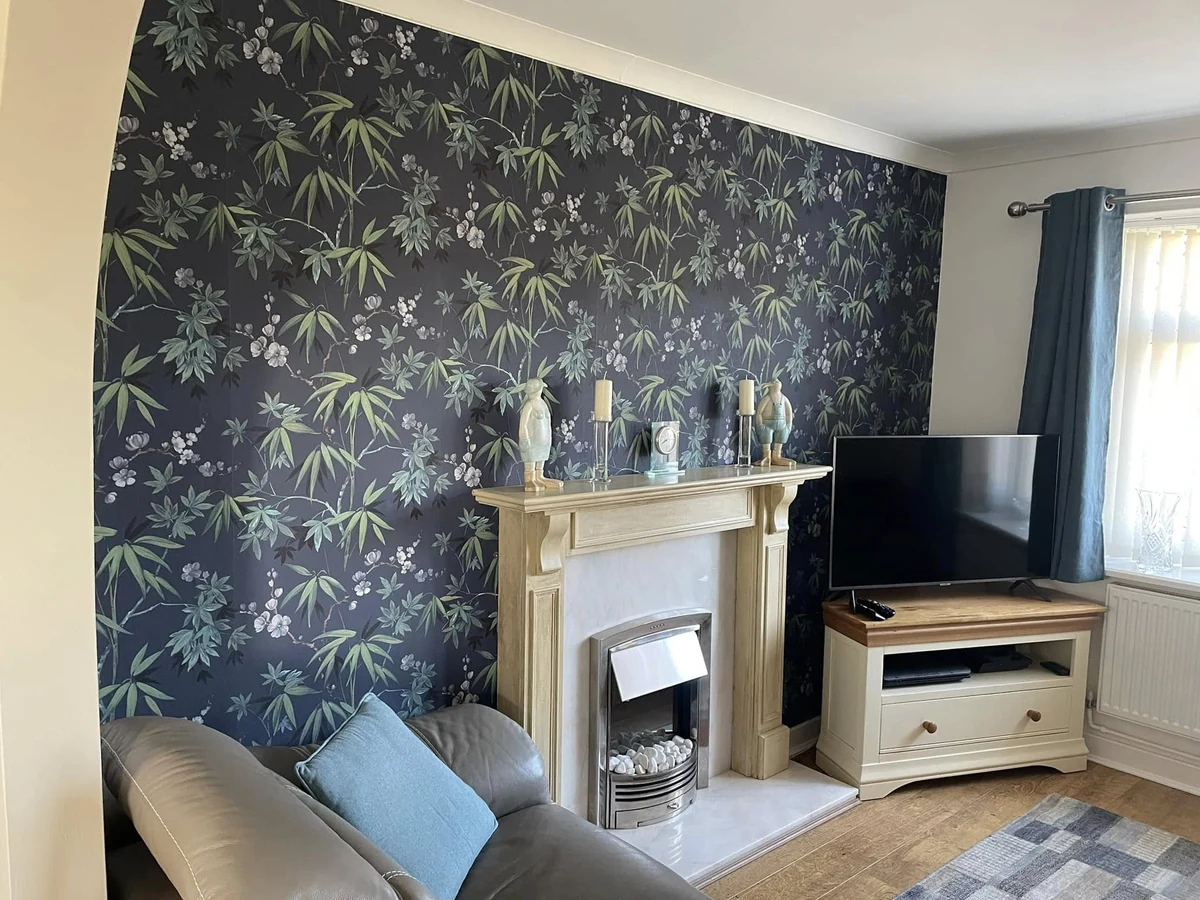 Finished room with a dark botanical feature wall, fireplace and seating in a Swansea home