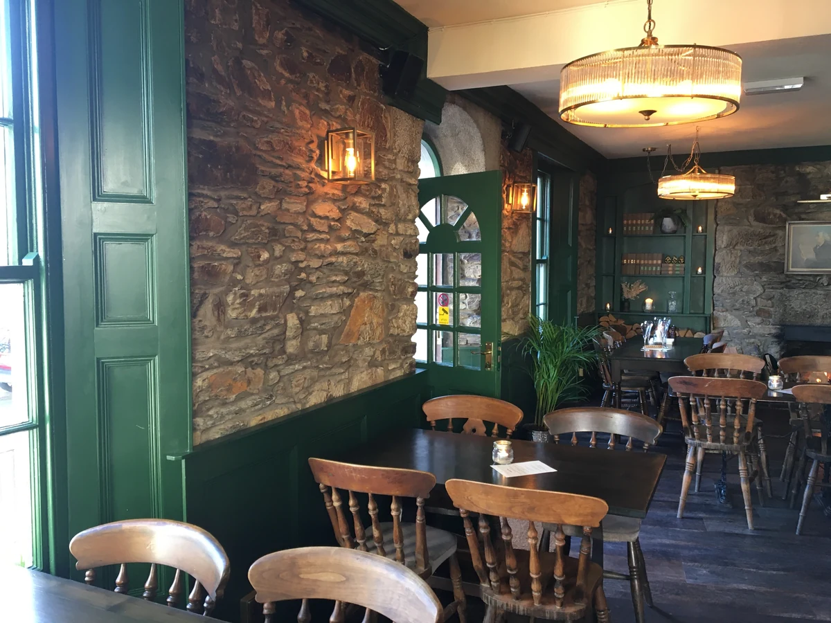 Finished pub seating area with stone walls, green joinery and feature lighting in Swansea