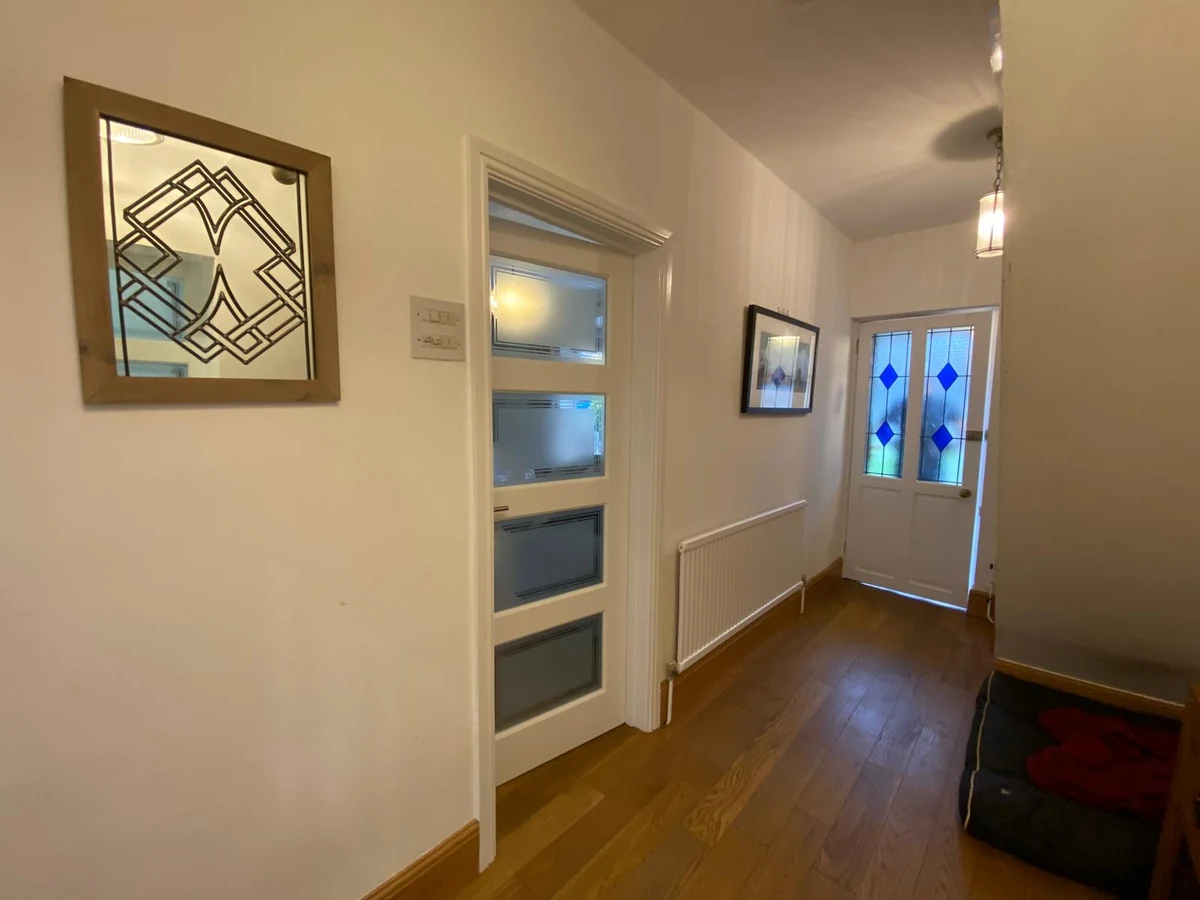 Finished Swansea hallway with a stained glass front door and new wood flooring