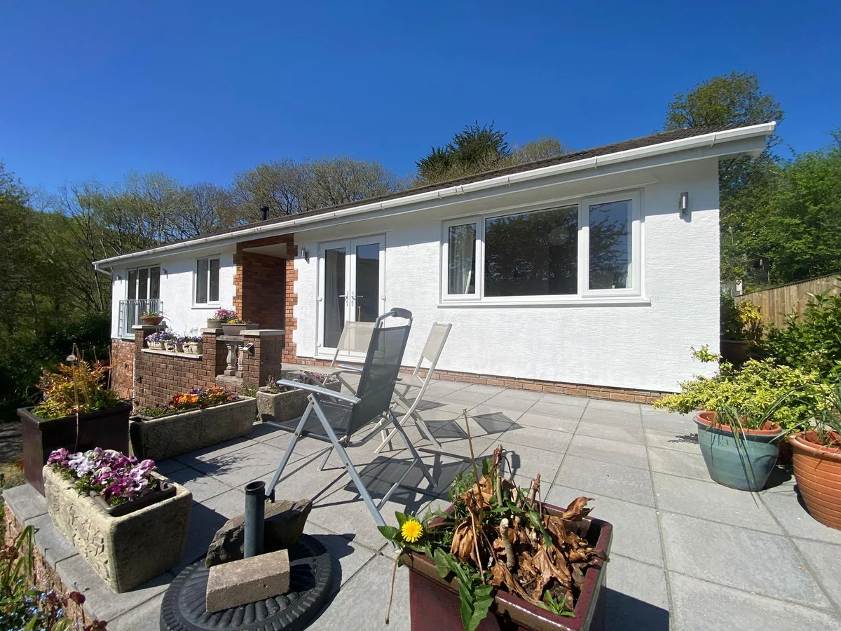 Finished white exterior and paved patio on a single-storey Swansea home in bright sun