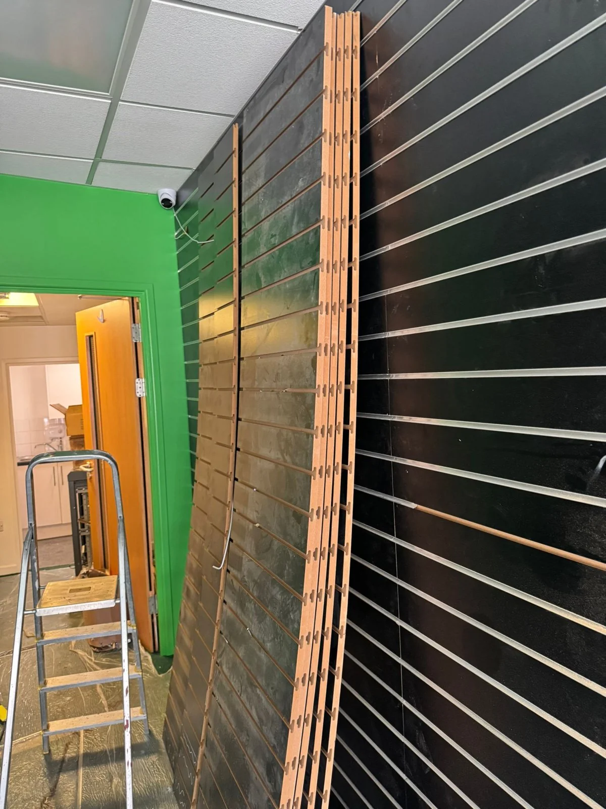 Black slatwall display panelling being installed inside the Wimozee Technology shop fit-out, Morriston